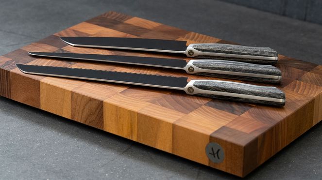 
                    Tagliere di legno di noce Caminada con la seria di coltelli legno di frassino Caminada
